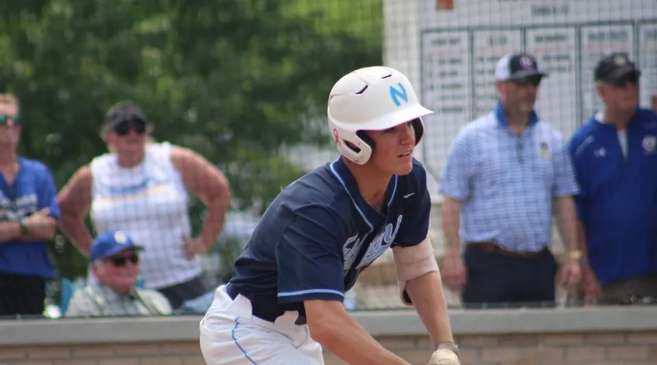 Un giovane giocatore di baseball in divisa sta in primo piano nel campo sportivo della Northpoint Christian School.