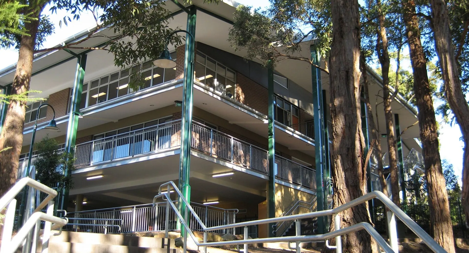 L'edificio a più piani della The Hills Grammar School con balconi è circondato da alti alberi.