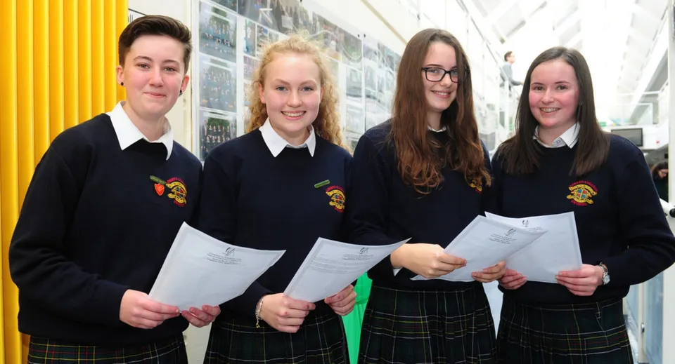 Quattro studenti nel corridoio del Fingal Community College indossano la divisa scolastica e tengono in mano dei fogli.