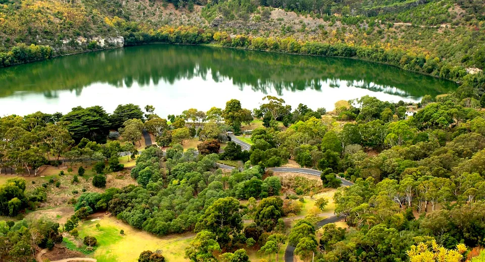 Un paesaggio verde con un lago calmo e un bosco sullo sfondo, vicino alla Grant High School.