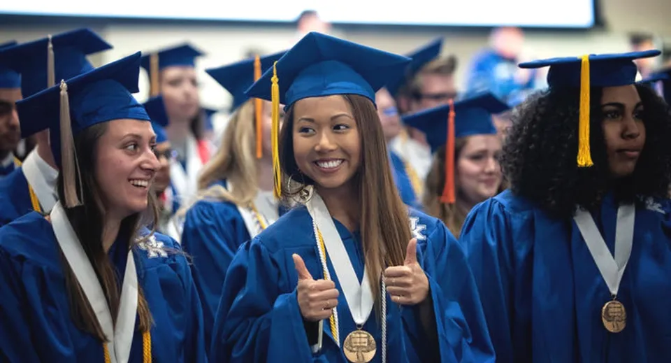 Un gruppo di diplomati dell'Elizabeth College festeggia il conseguimento del titolo in toga blu.