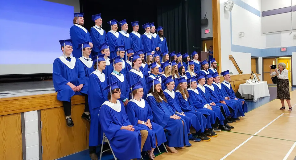 Un grande gruppo di diplomati della Ridgetown District High School è sul palco in toga blu durante la cerimonia di diploma.