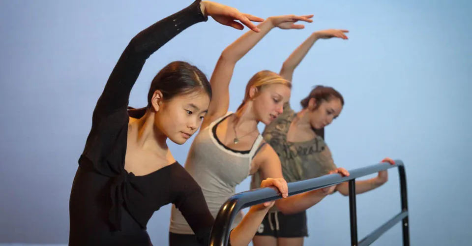 Tre studentesse eseguono una coreografia di danza in abbigliamento sportivo nel campus del Waterloo Catholic District School Board.