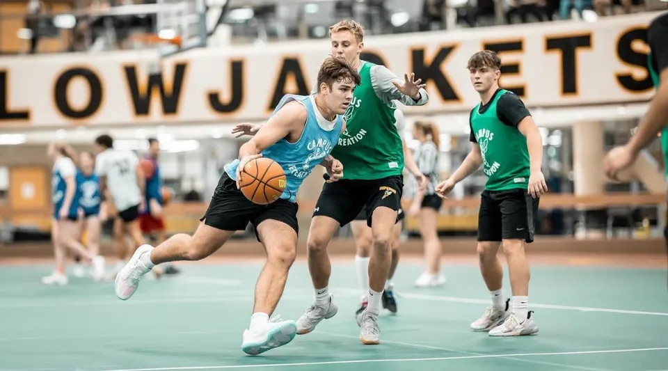 Un gruppo di studenti gioca a basket nella palestra della University of Wisconsin-Superior davanti a un grande cartello LOWJACKETS.