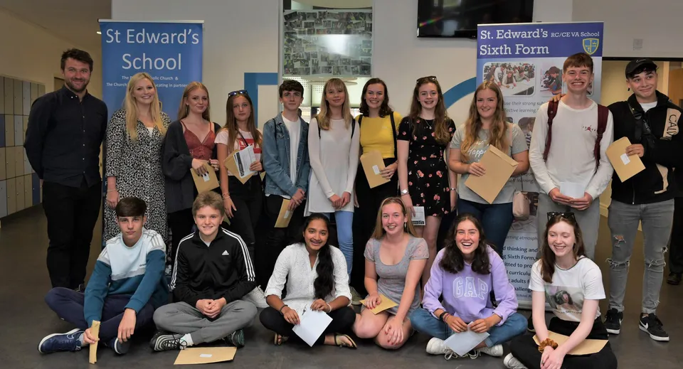 Un grupo de estudiantes está frente al logo de la St. Edward's School en Poole durante un evento escolar.