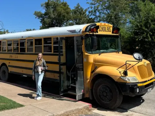 Chica bajando de un autobús escolar amarillo por la mañana