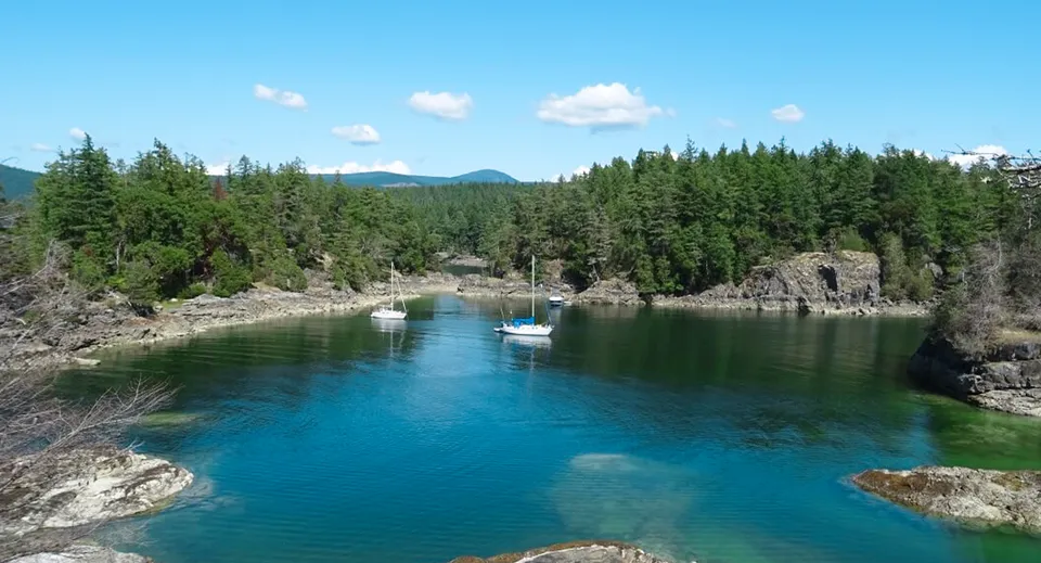 Un lago turchese circondato da foreste di conifere e rocce sotto un cielo cosparso di nuvole vicino alla Garibaldi Secondary School.