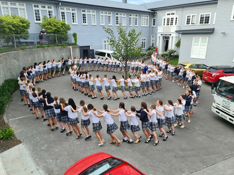 Un gruppo di studentesse della Napier Girls' High School sta all'aperto in una formazione circolare davanti all'edificio scolastico.