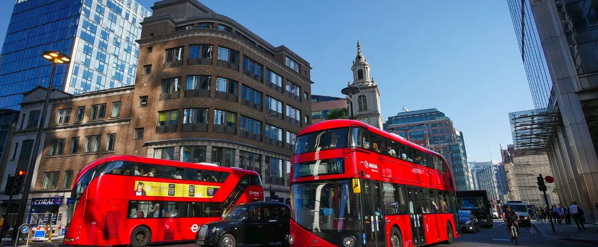 Due autobus rossi a due piani in una via della City di Londra tra i palazzi moderni