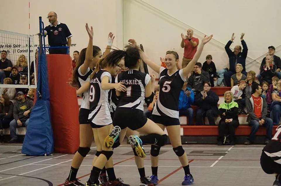 La squadra di pallavolo della Senator Gershaw School festeggia in campo durante una partita in palestra.