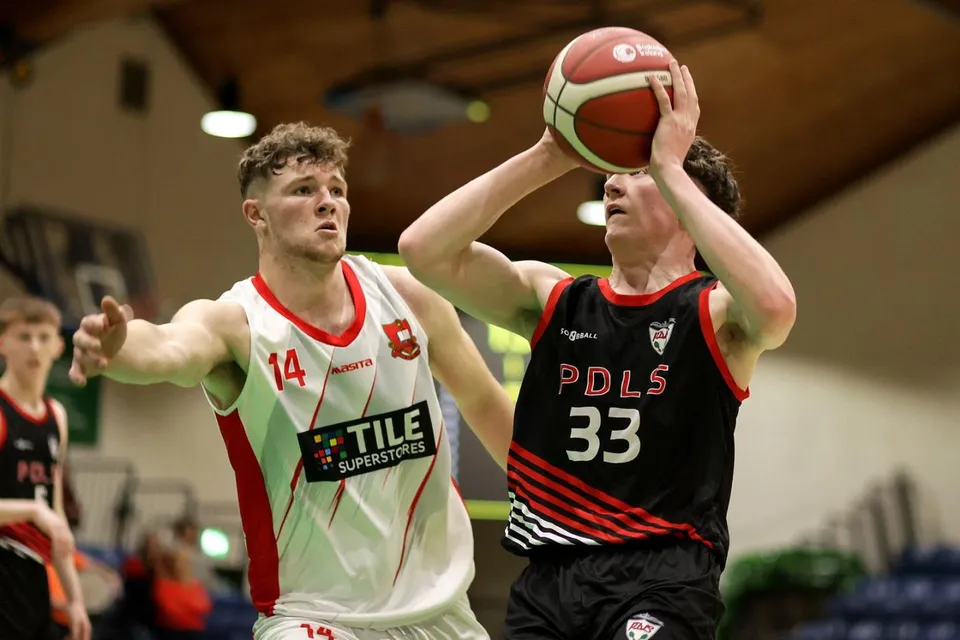 Due studenti del St. Muredach's College lottano per la palla durante una partita di basket sul campo.