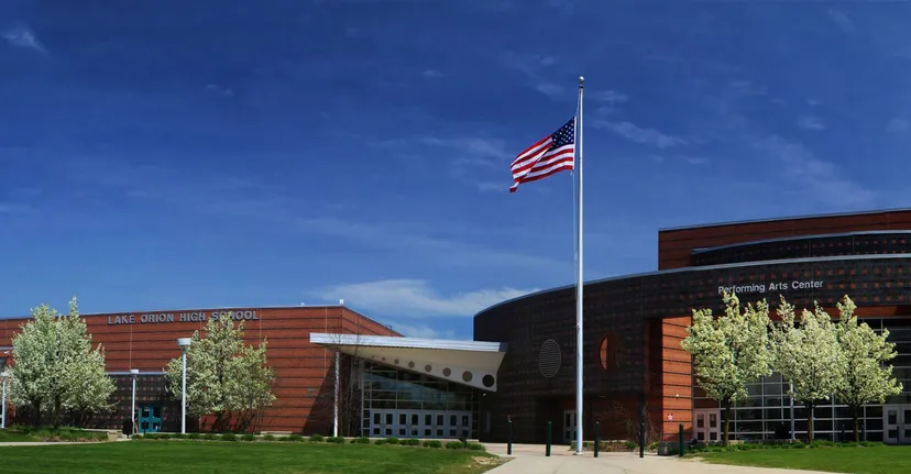 L'edificio scolastico moderno della Lake Orion High School con la bandiera americana e alberi nel campus scolastico.