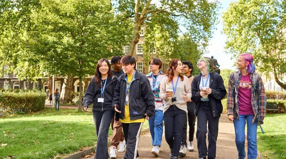 Un gruppo di studenti cammina insieme su un sentiero nel verde campus della Guildhouse School London.