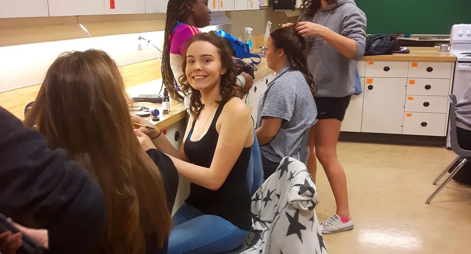 Studentesse della Charles Bloom Secondary School interagiscono e sorridono in classe.