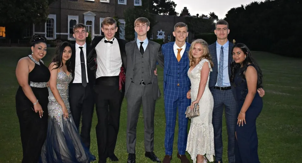 Un gruppo di persone posa davanti all'edificio della St. Brendan’s Community School durante un evento formale.