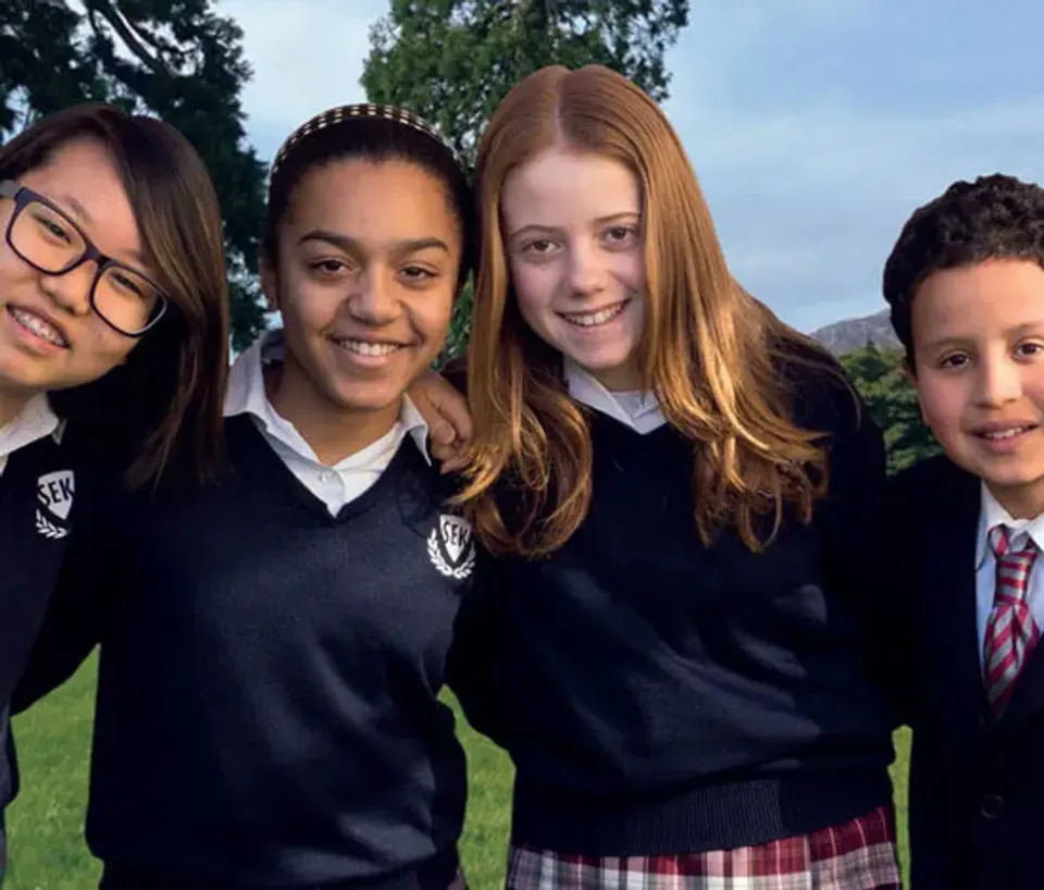 Quattro studenti della SEK International School Dublin posano sorridenti all'aperto con le loro uniformi scolastiche.
