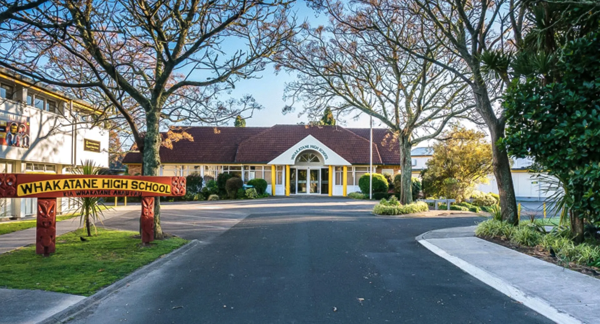 L'edificio scolastico della Whakatane High School circondato da alberi e con un ingresso pavimentato.