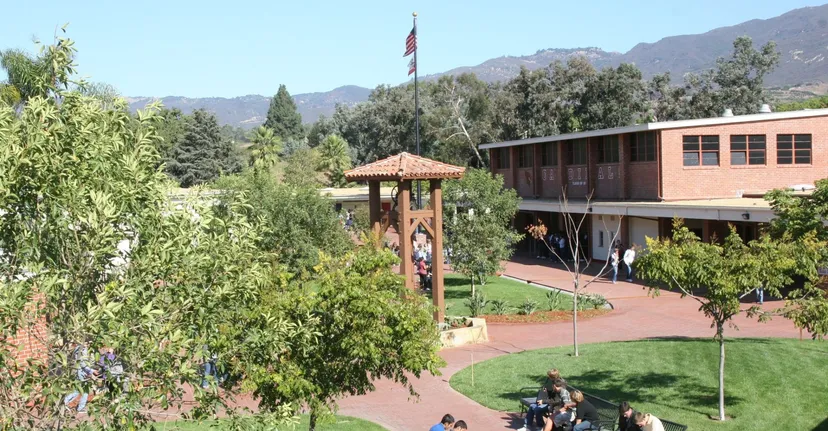 Il campus della Bishop Garcia Diego High School con una torre campanaria in legno, aree verdi ed edifici di fronte alle montagne.