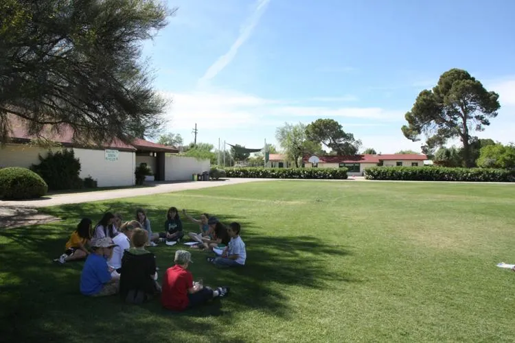 Un grupo de estudiantes está de pie sobre el césped en el recinto de Green Fields High School.