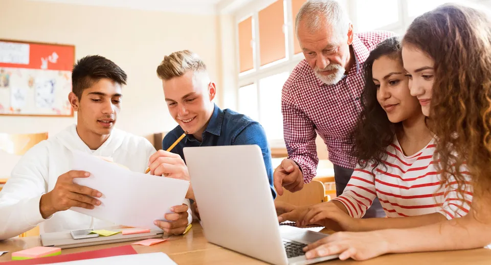 Un gruppo di persone lavora insieme a un computer portatile nel campus del Coláiste Bhaile Chláir.