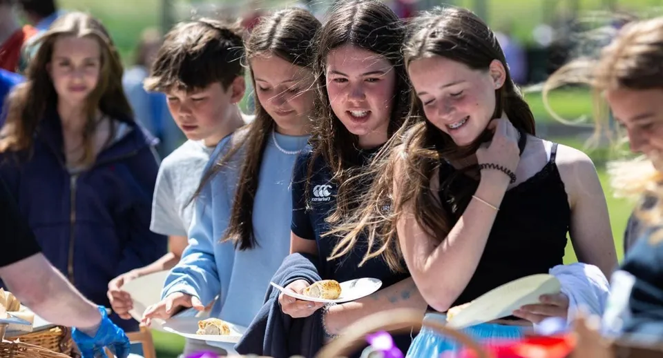 Un gruppo di studentesse e studenti della Scoil Ruáin chiacchiera ridendo all'aperto nel campus della scuola.