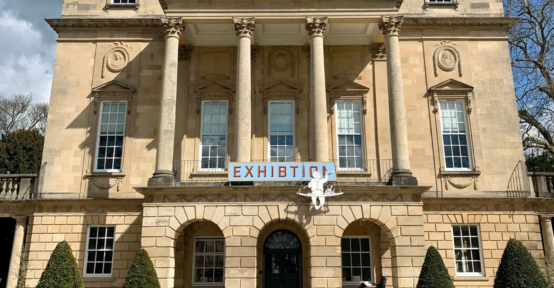 L'edificio principale neoclassico della Bath Academy è circondato da alberi e si trova su una piazza pavimentata.