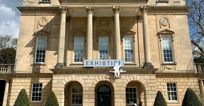 L'edificio principale neoclassico della Bath Academy è circondato da alberi e si trova su una piazza pavimentata.