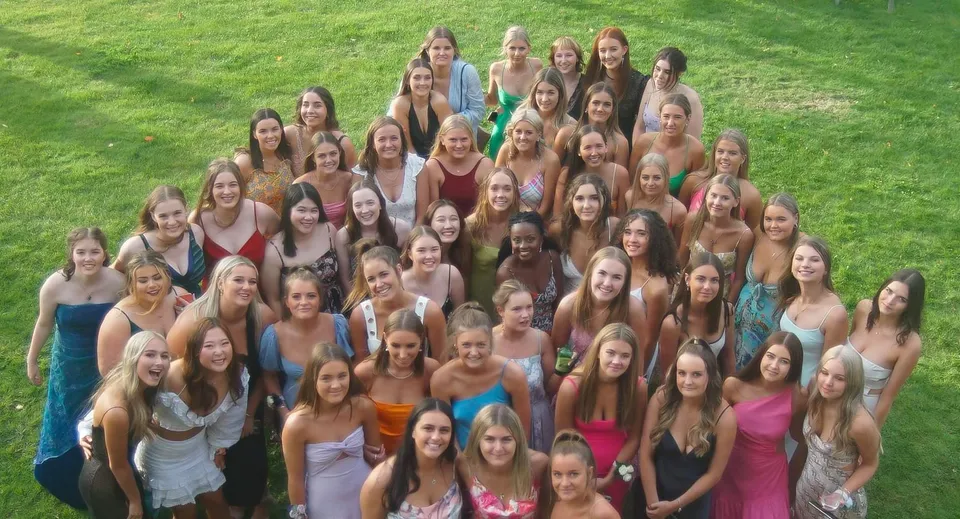 Un gruppo di giovani studentesse di Woodford House posa su un prato con outfit colorati.