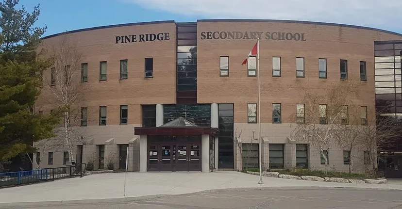 L'edificio in mattoni della Pine Ridge Secondary School è visibile con il nome sulla facciata sotto un cielo limpido.