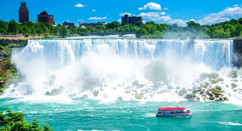Una barca rossa con passeggeri naviga davanti a una cascata nell'area della Moscrop School.