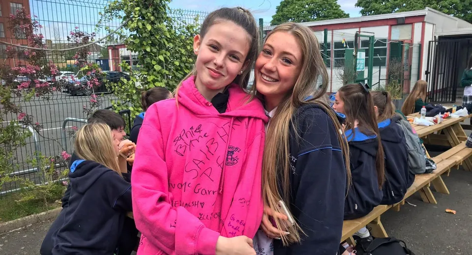 Due studentesse con lunghi capelli biondi sono insieme e sorridono nel campus della St. Mary's Secondary School Charleville.