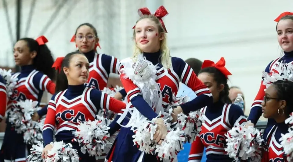 Le cheerleader della Freedom Christian Academy si esibiscono con i pompon su un palco o su un campo da gioco.