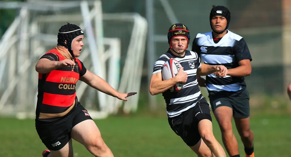 Tre giocatori di rugby in azione sul campo sportivo della South England International School Brighton.