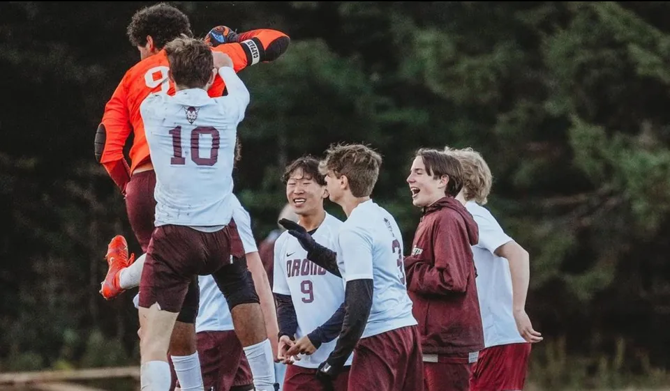 Un gruppo di studenti della Orono High School si riunisce all'aperto davanti ad alberi e spazi verdi.