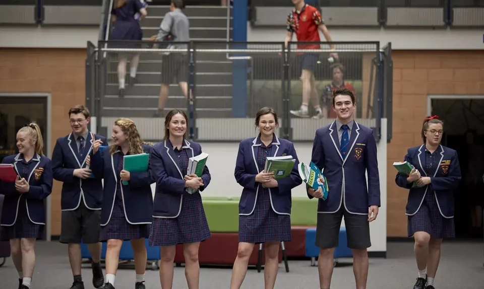 Un gruppo di studenti in uniforme scolastica si trova nel corridoio del campus del Trinity College.