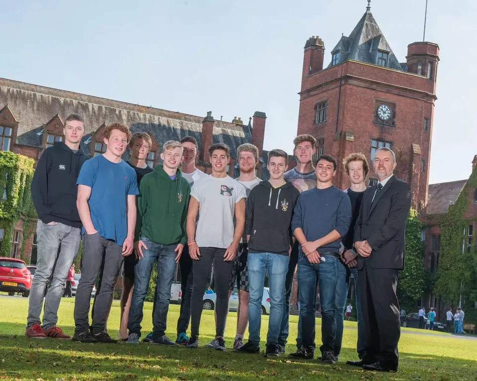 Un gruppo di studenti è in piedi davanti a un edificio in mattoni con torre dell'orologio nel campus del Campbell College.