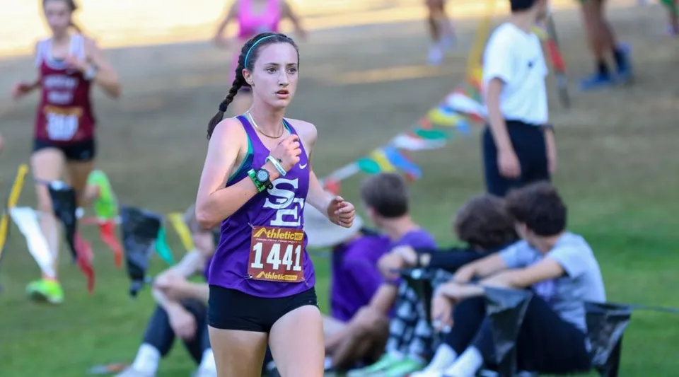 Una corridrice con la maglia viola partecipa a una competizione nei terreni dell'Eugene School District.