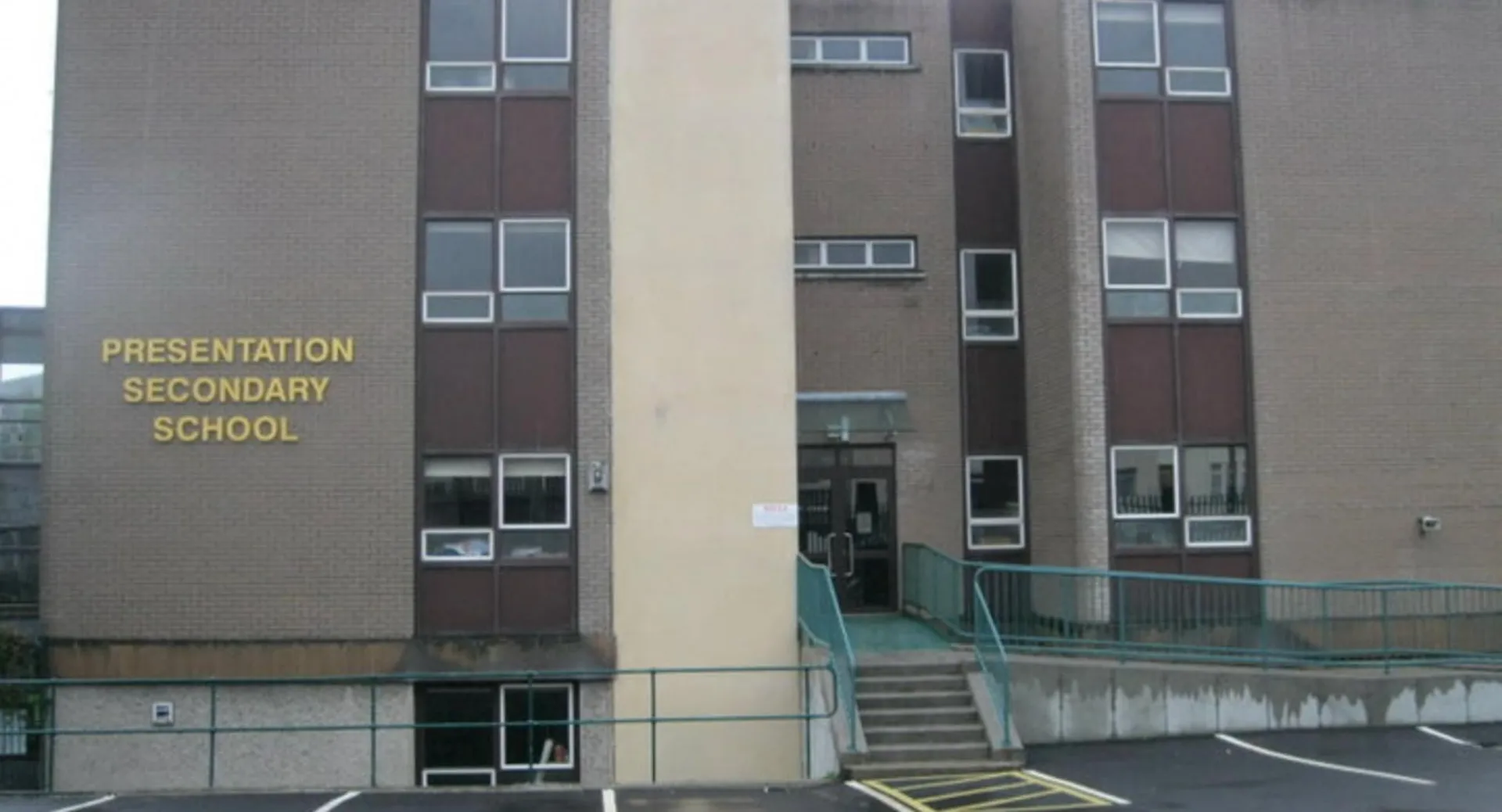 Si vede l'edificio a più piani in mattoni della Presentation Secondary School a Cork con un parcheggio circostante.