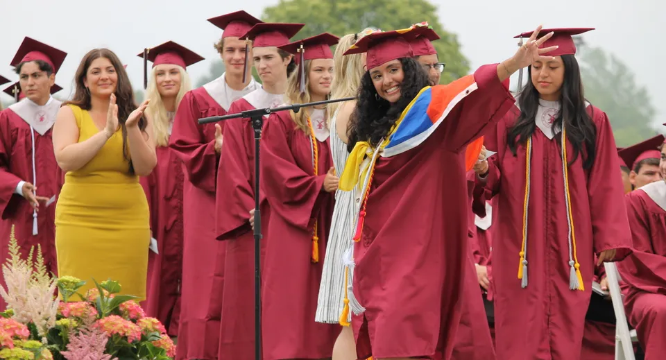 Un gruppo di diplomate e diplomati della Palm Beach Currumbin State High School è insieme davanti a uno sfondo di piante verdi.