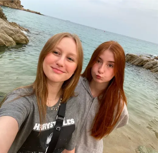 Zwei Mädchen machen ein Selfie an einem Felsstrand in England