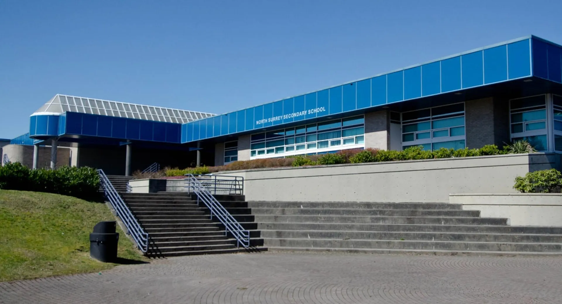 L'edificio principale moderno della North Surrey Secondary School con scalinate e un prato in primo piano.