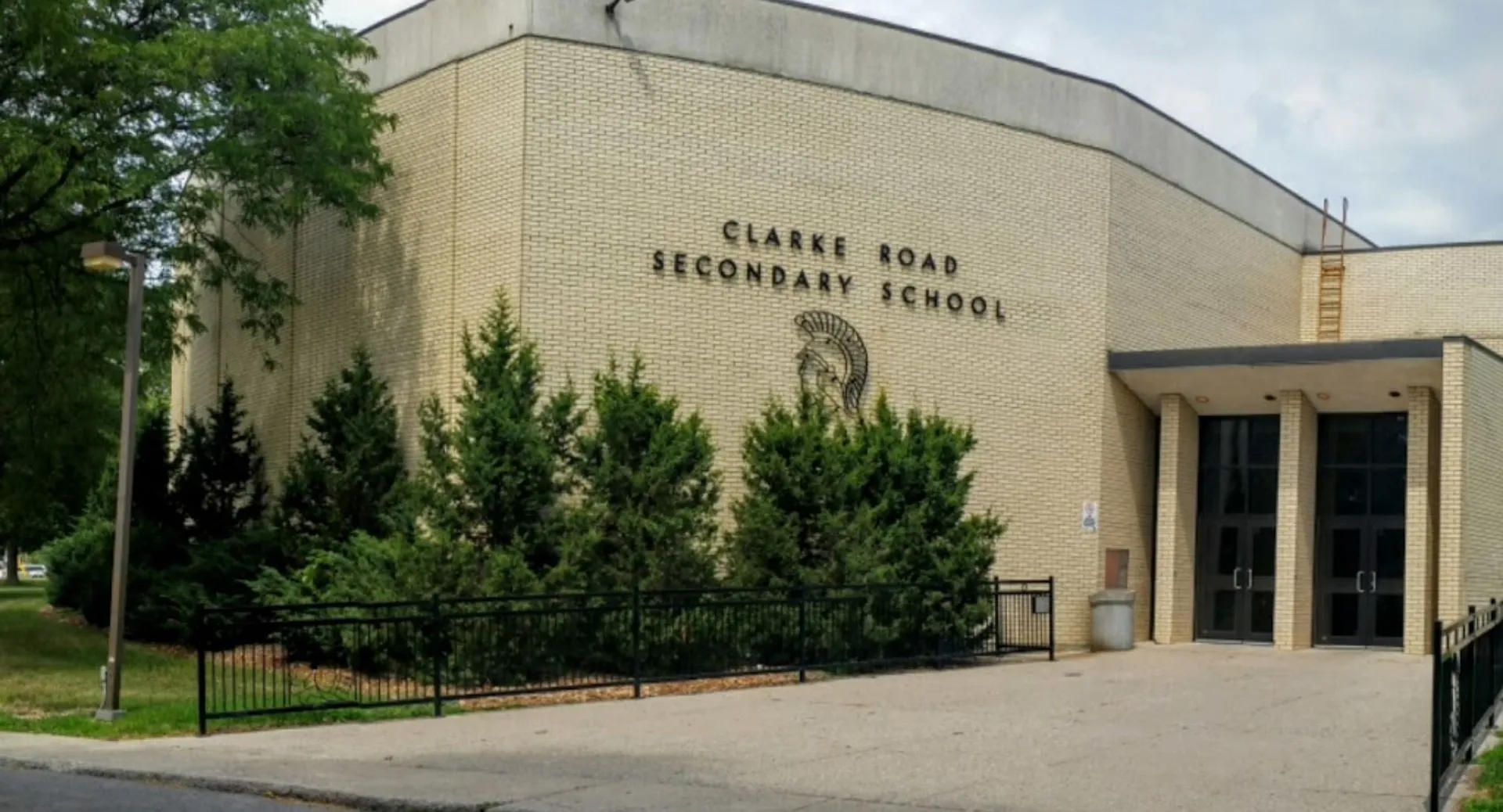 L'edificio in mattoni della Clarke Road Secondary School è circondato da alberi e da una recinzione metallica.
