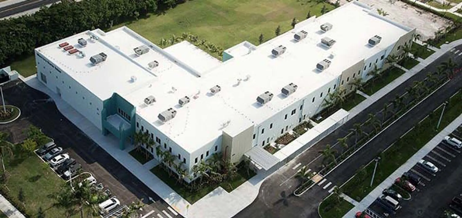 L'edificio scolastico moderno e a più piani della Miami Arts Charter School, circondato da spazi verdi e veicoli parcheggiati.