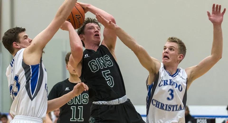 Tre studenti della Glenlyon Norfolk School si contendono la palla sul campo da basket.