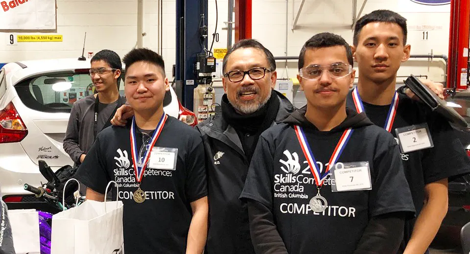 Un gruppo di studenti della Britannia Secondary School con magliette nere si trova nell'area dell'officina.