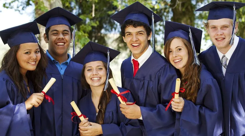 I diplomati e le diplomate della All Saints Catholic Secondary School si trovano davanti agli alberi indossando la toga.