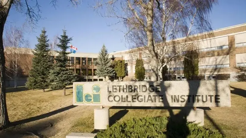 Un cartello del Lethbridge Collegiate Institute è visibile in primo piano davanti ad alberi e a un edificio.