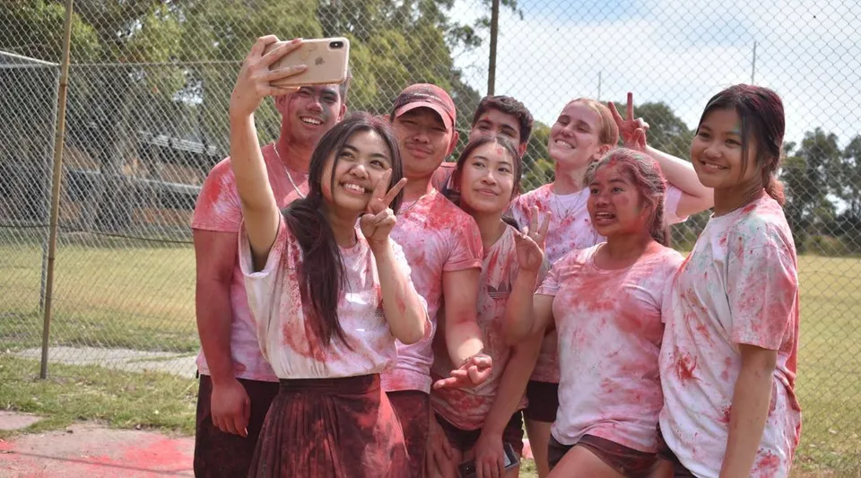 Studentesse della Girrawheen Senior High School si scattano un selfie insieme all'aperto con della polvere rosa.