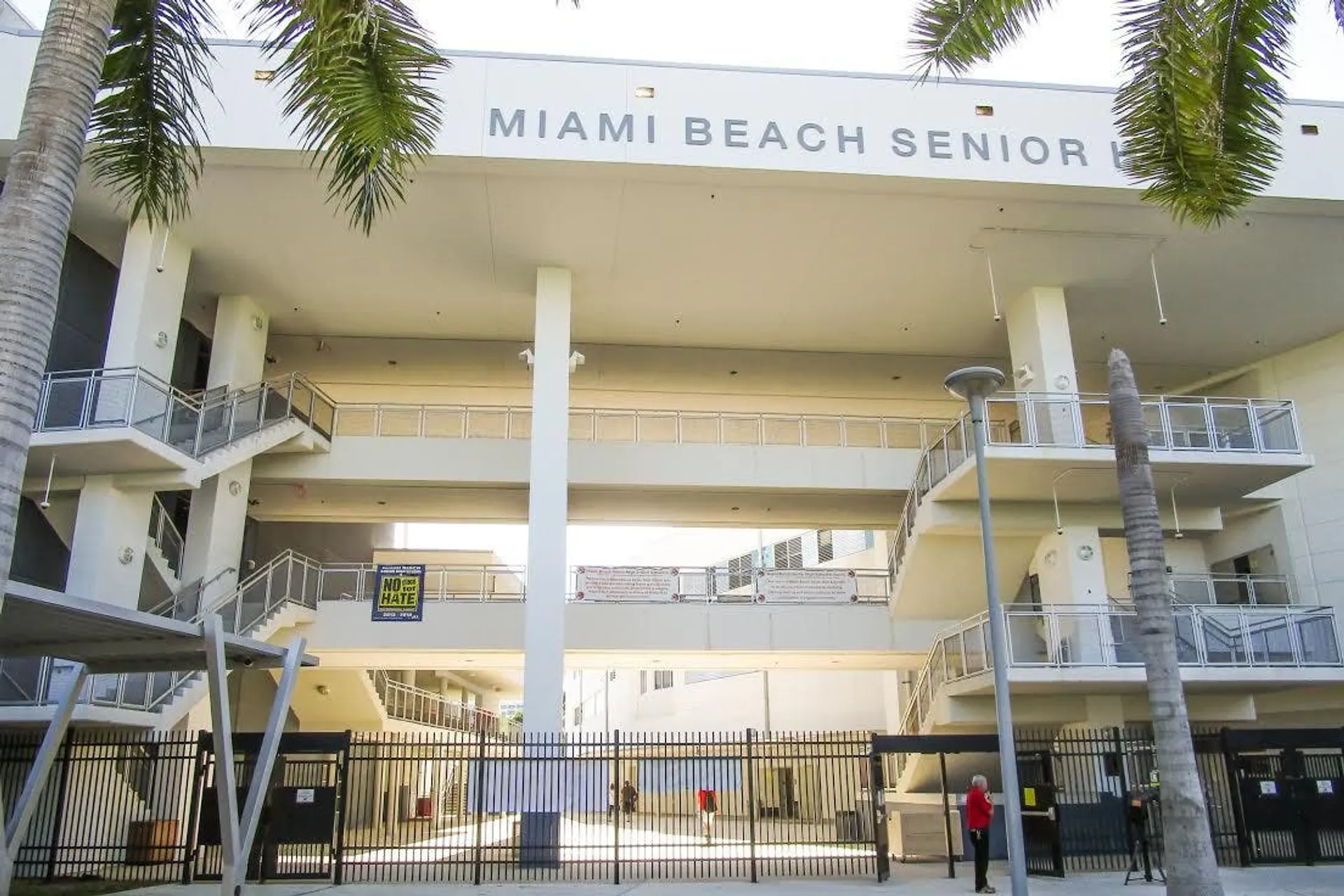 L'edificio a più piani della Miami Beach Senior High School è circondato da palme e delimitato da una recinzione.