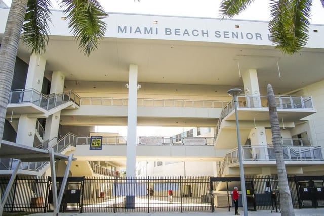 Das mehrstöckige Gebäude der Miami Beach Senior High School ist von Palmen umgeben und durch einen Zaun abgegrenzt.